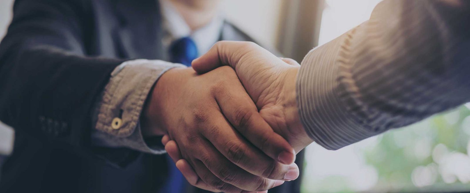 Two people shaking hands over a completed agreement after a contract review