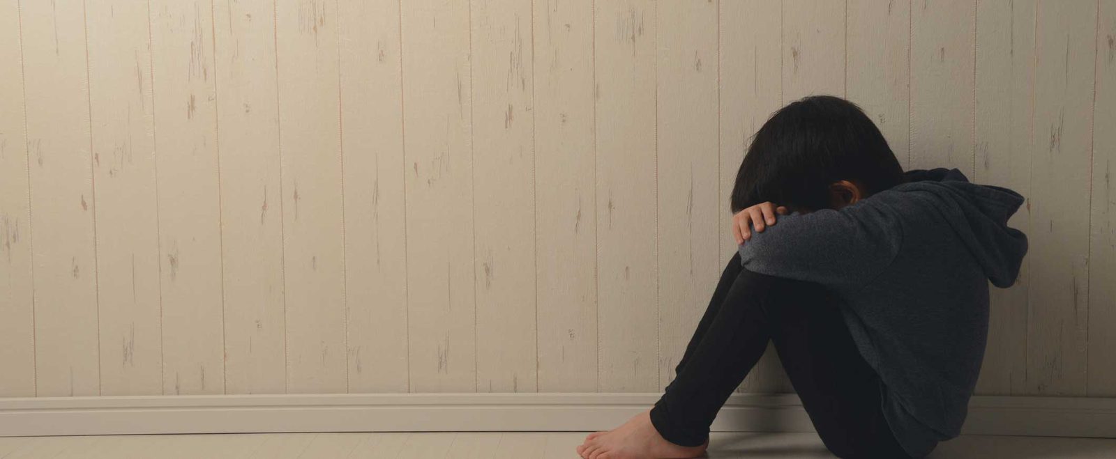 A child sitting alone with their head down in a child abuse and neglect case