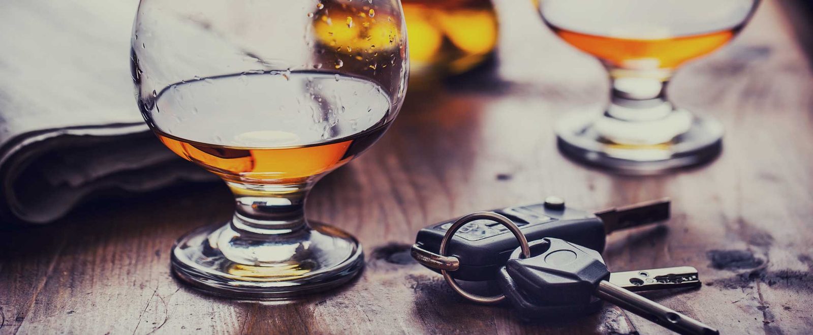 Two glasses of liquor beside car keys on a bar, the setup behind a DUI arrest