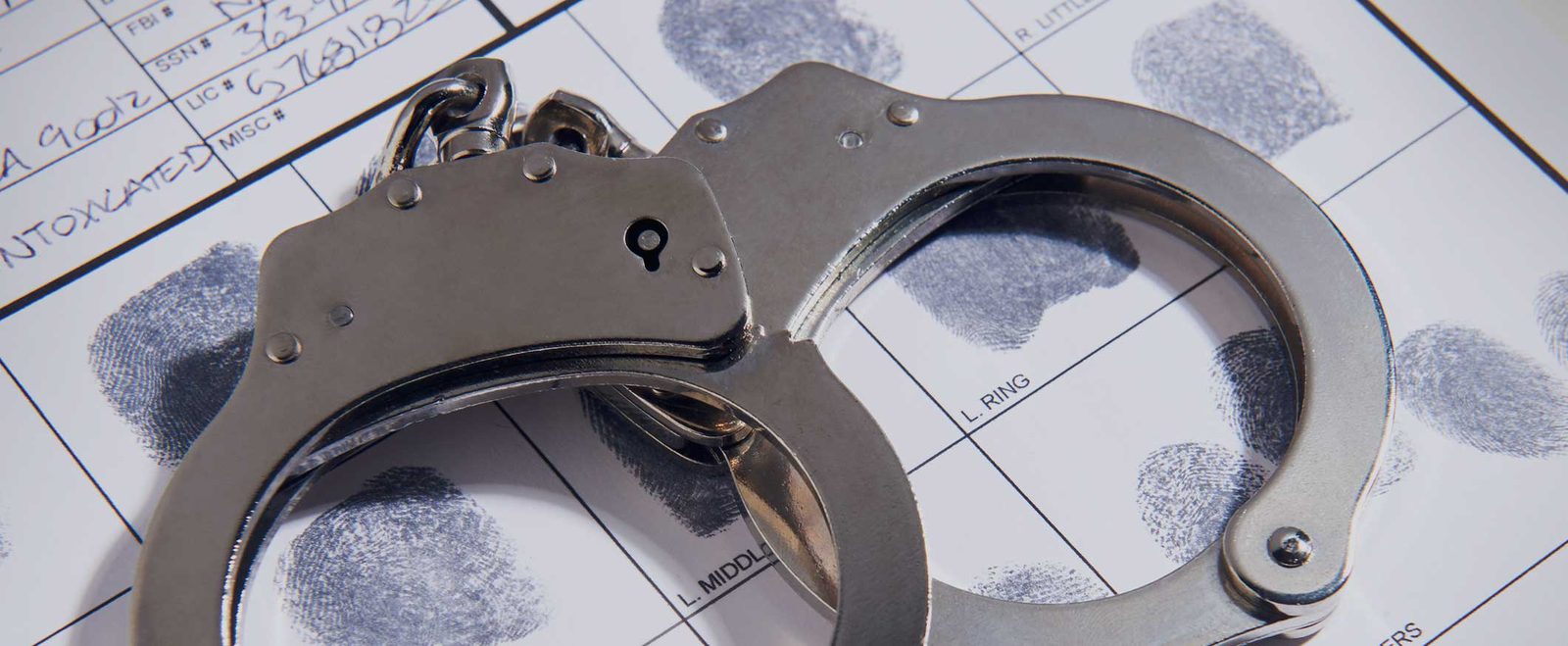 Handcuffs resting on a fingerprint record card, the record an expungement clears