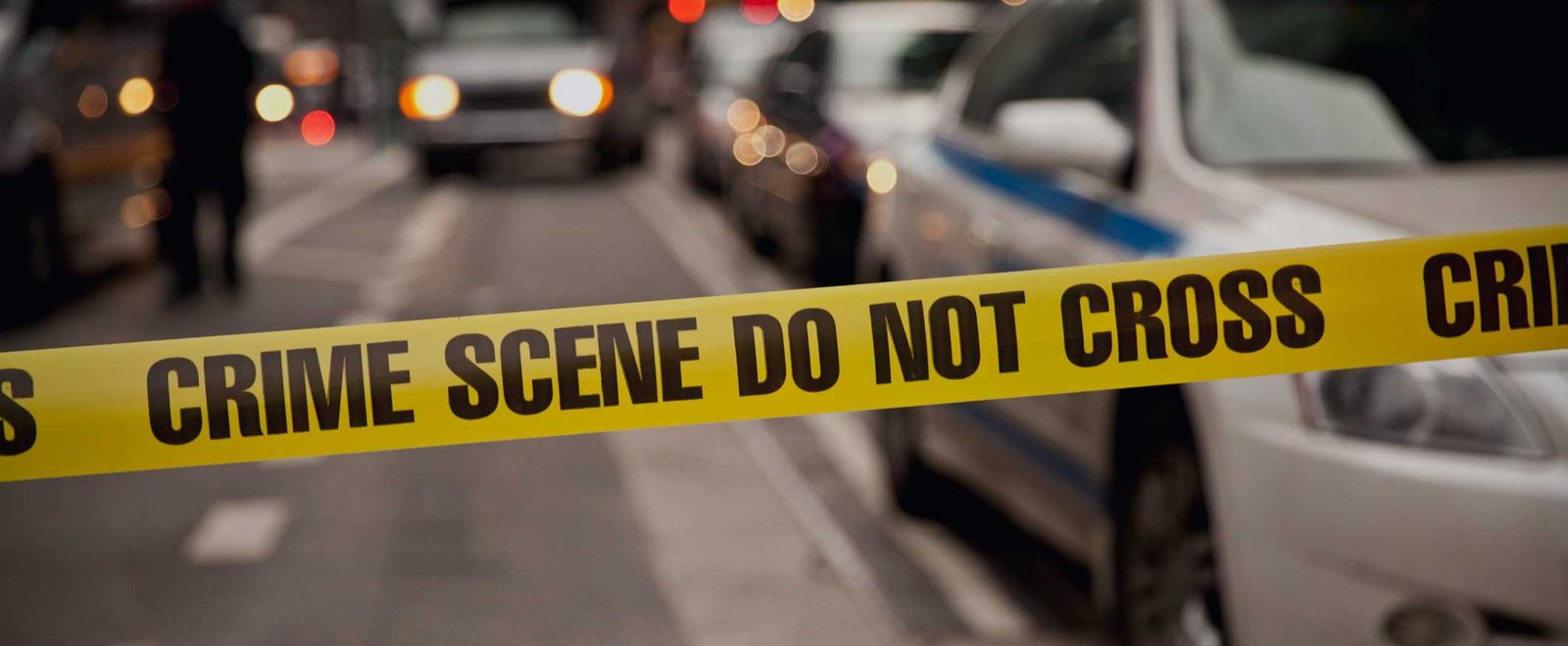 Police cars parked behind crime scene tape during a felony investigation