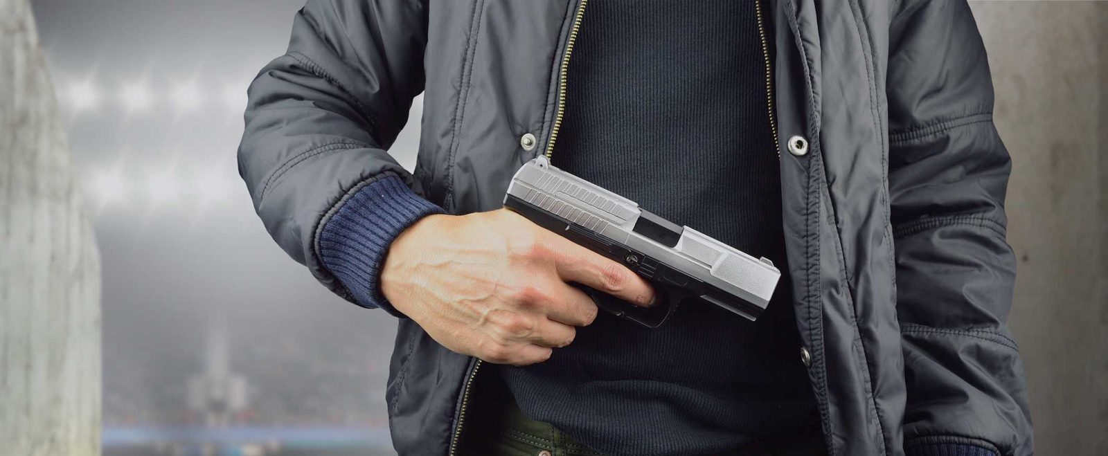 A man holding a handgun at his side, the weapon behind a gun crime charge