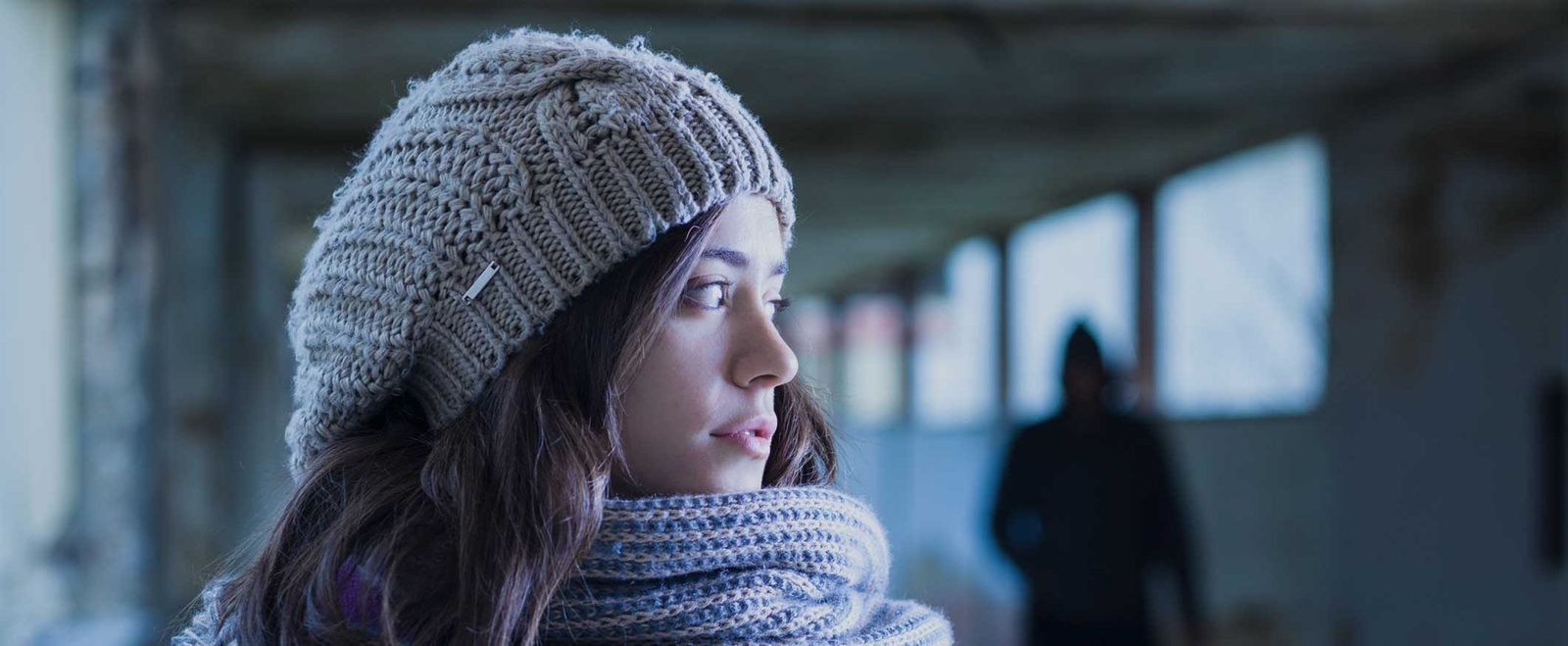 A woman glancing back at a shadowed figure following her in a stalking case