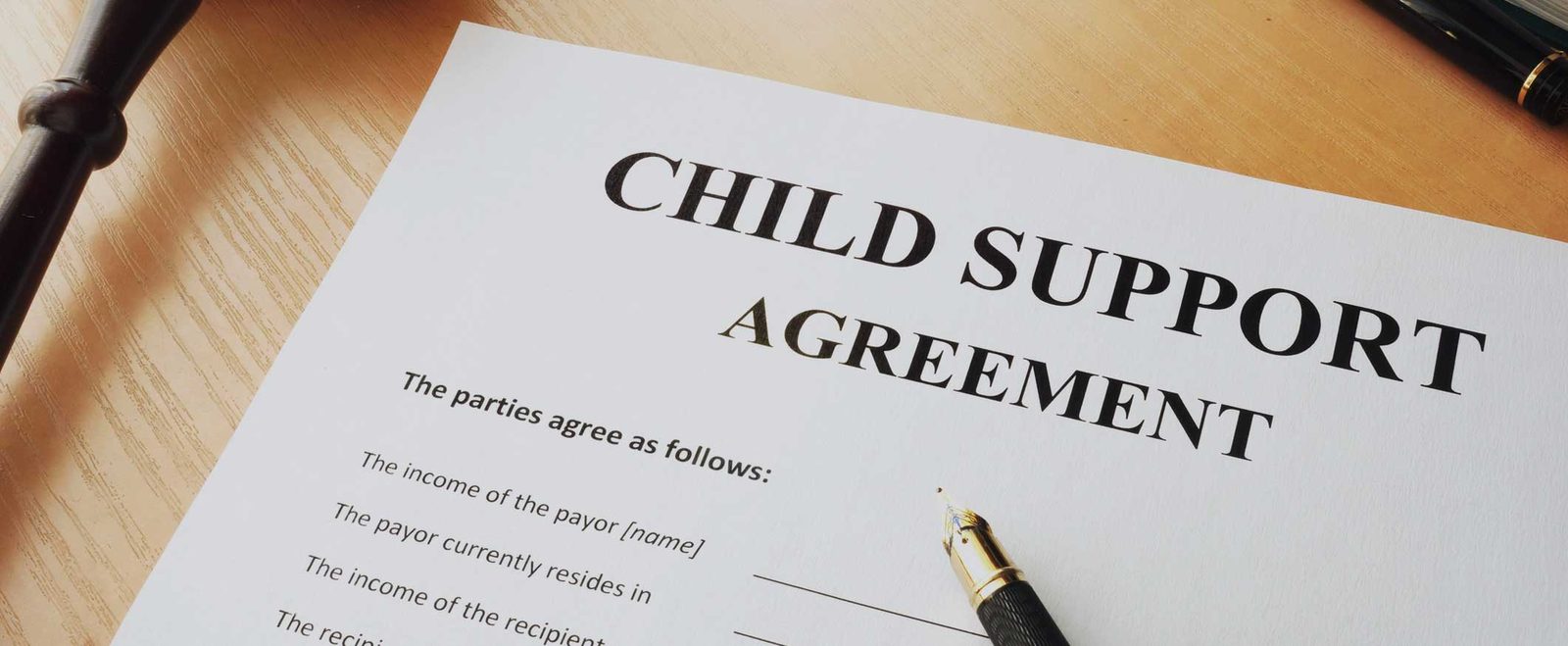 A child support agreement on a desk with a pen, ready to be signed