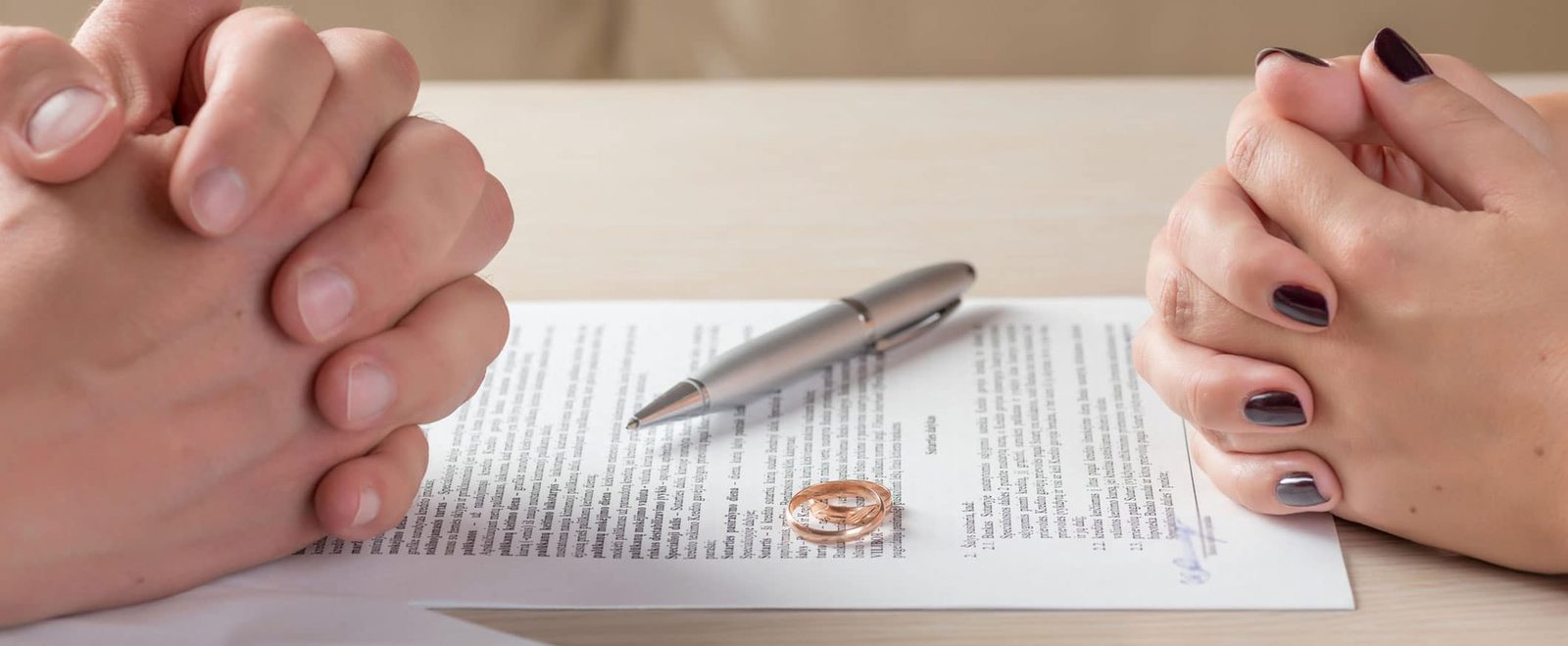A couple across a document with a pen and wedding ring, settling a family law matter