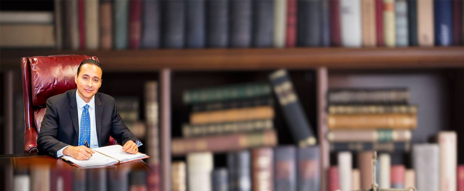 Attorney Alejo Lugo working at his desk in front of a wall of law books