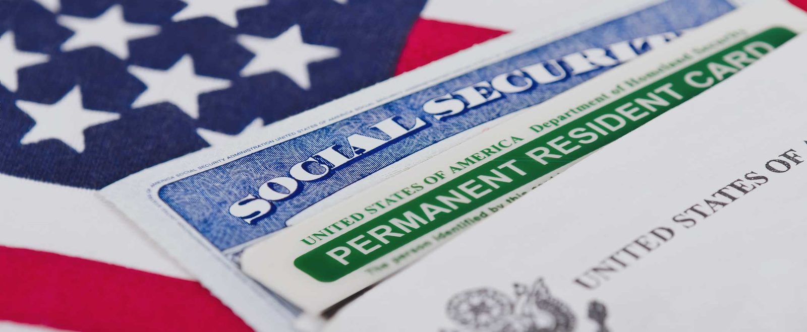 A Social Security card and permanent resident card on a flag after an adjustment of status