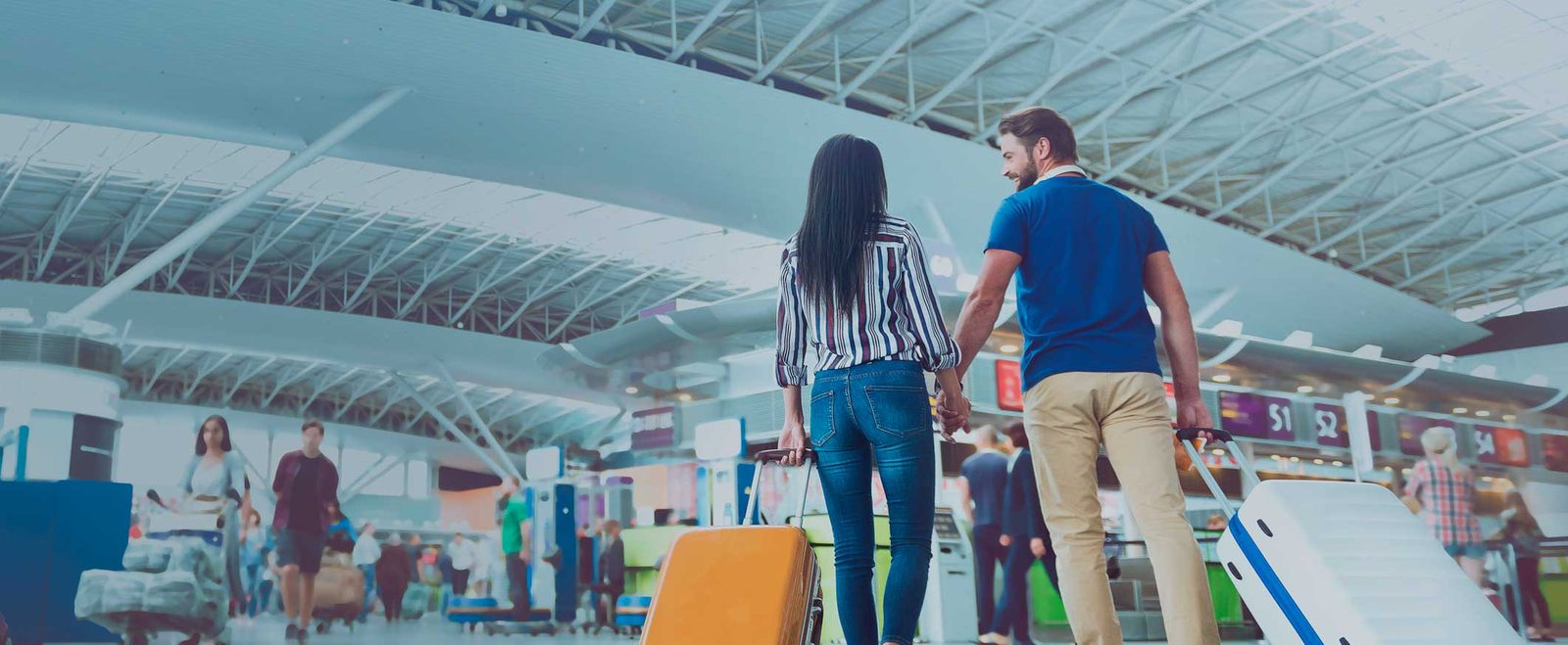 A couple walking through an airport with luggage after moving family members to the US