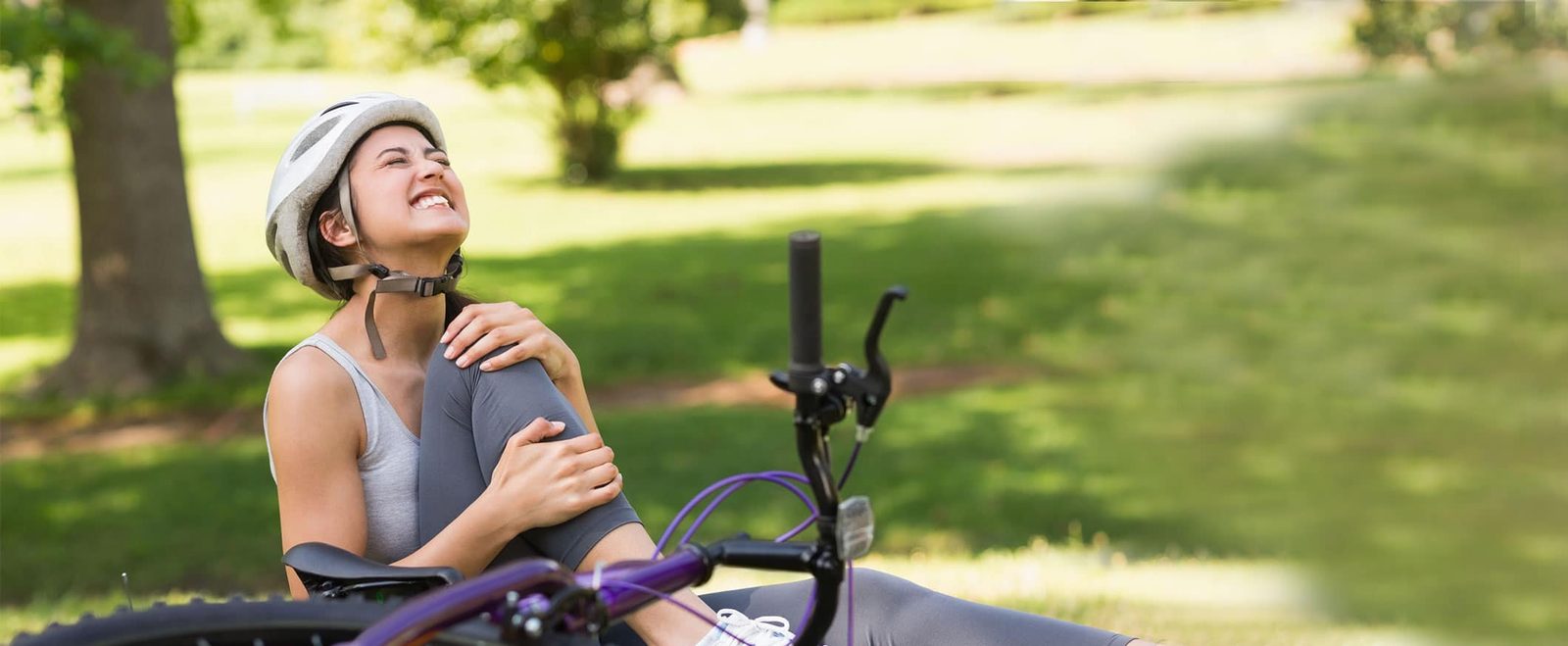 A woman holding her injured shoulder after falling from her bicycle, a personal injury